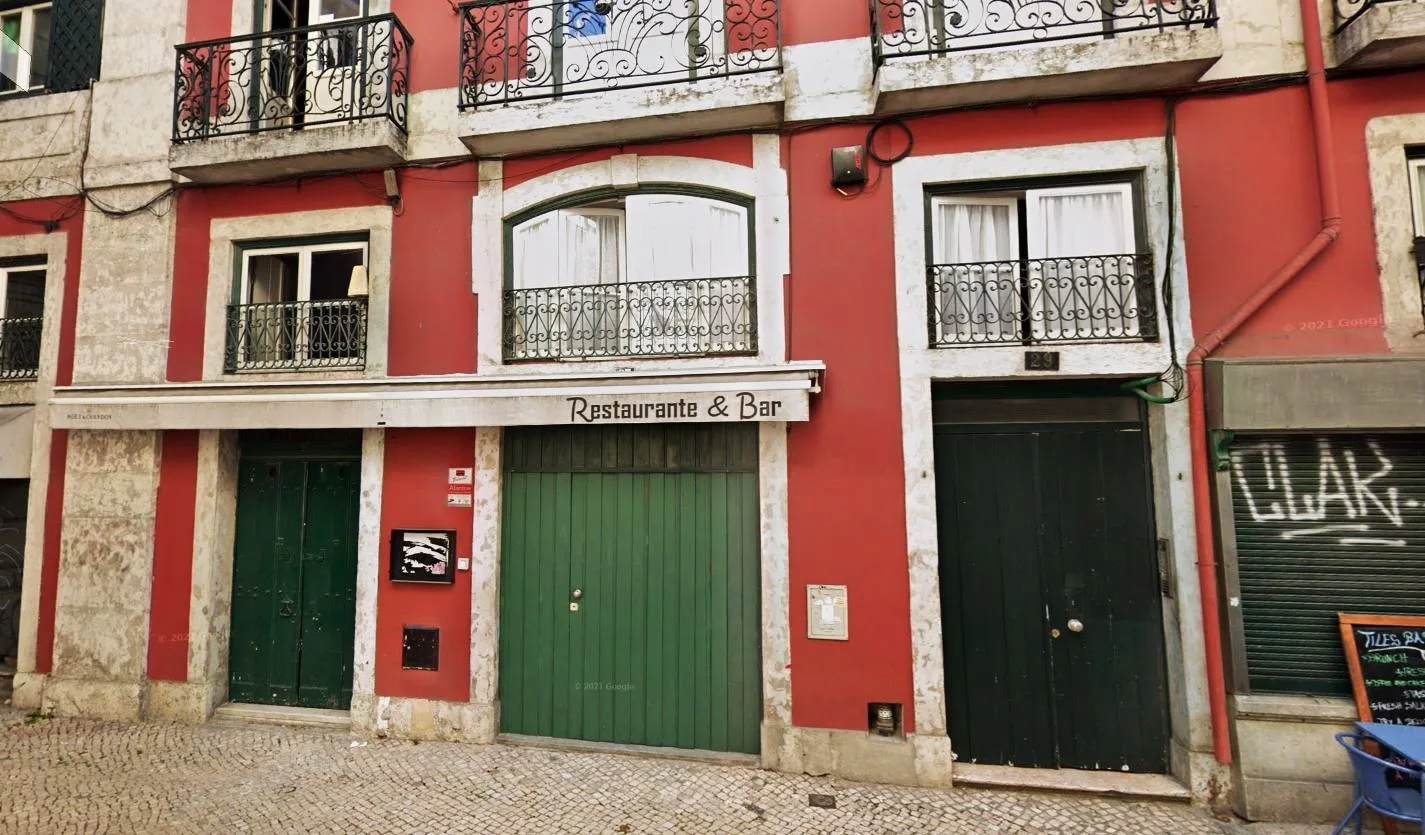 Edificio rojo a pie de calle con balcones y entradas en la planta baja.