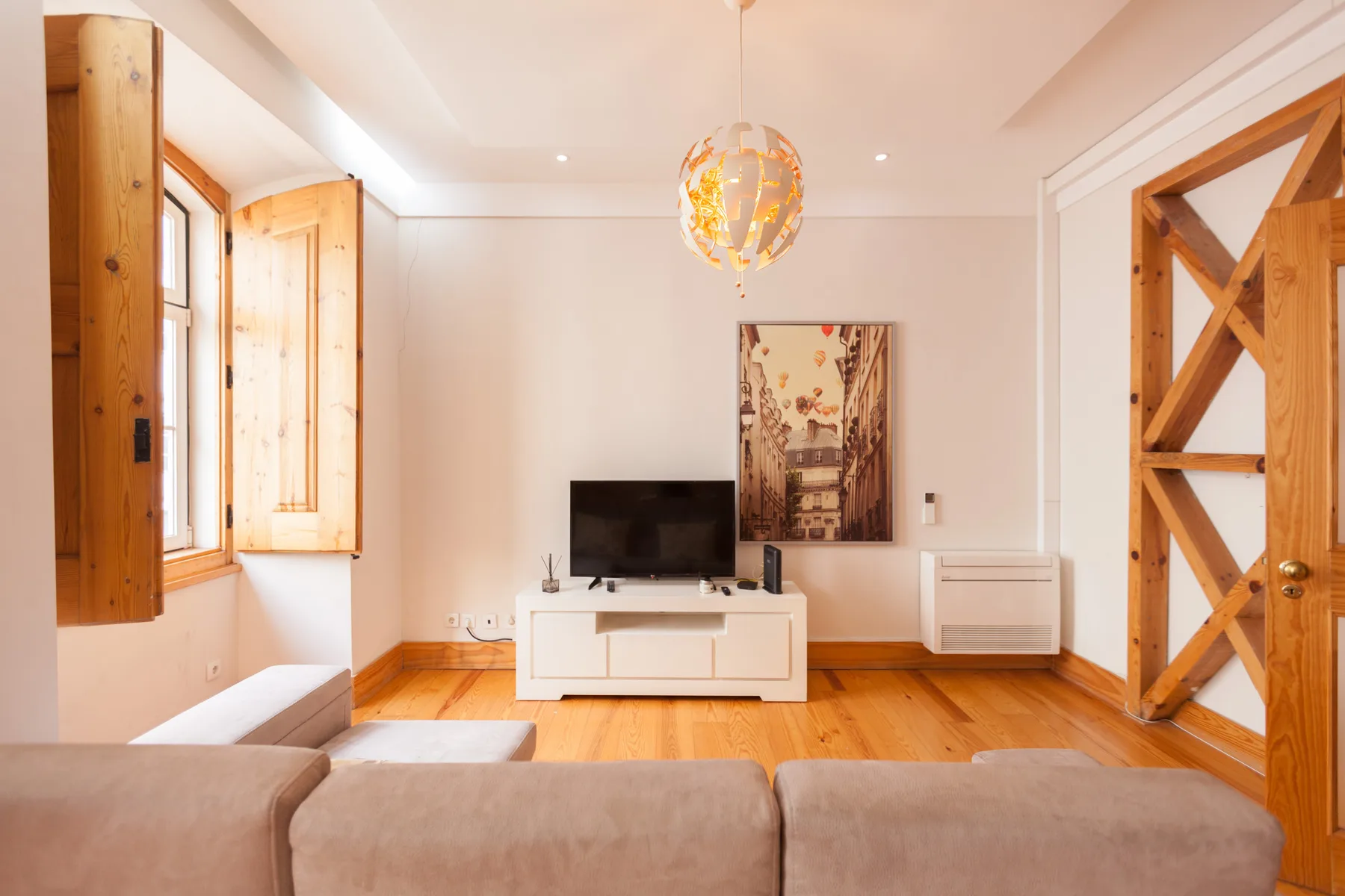 Una sala de estar luminosa con asientos, un televisor y suelo de madera.