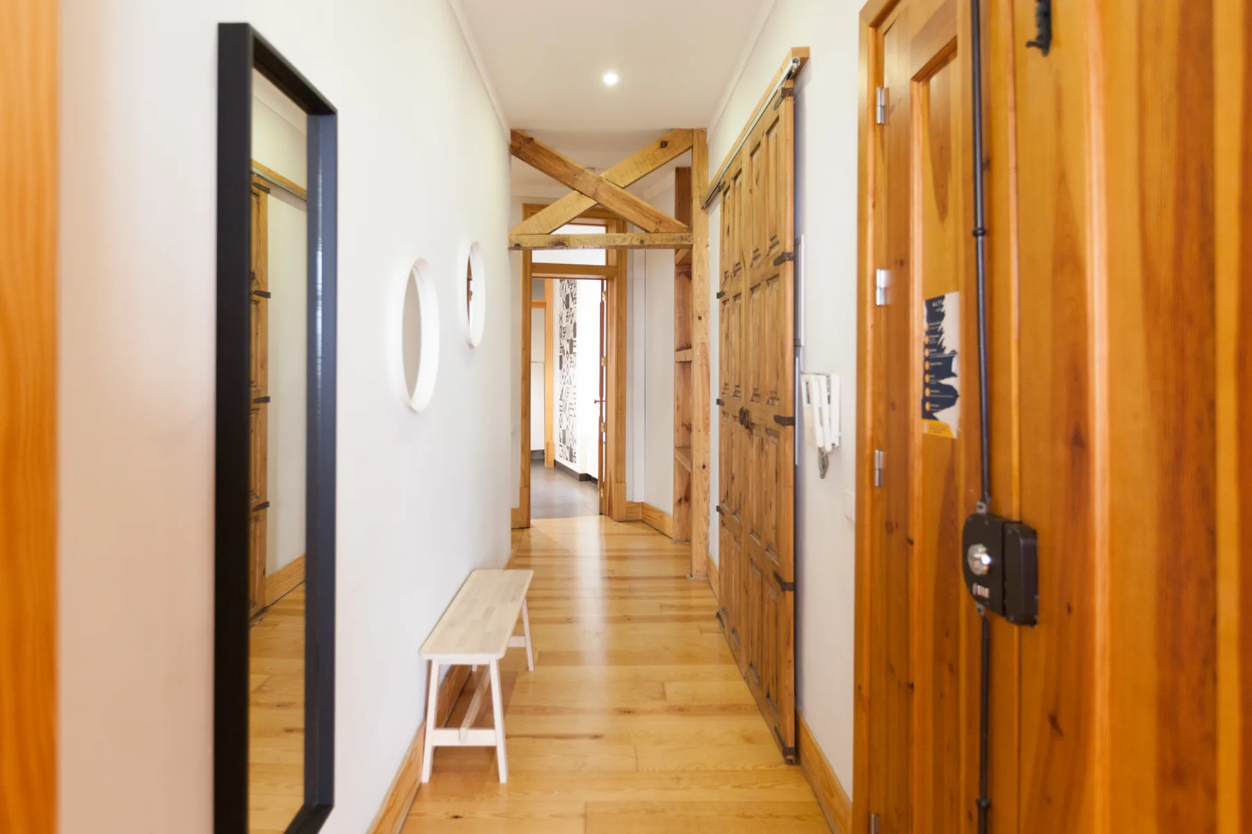 Un pasillo estrecho con puertas de madera y un pequeño banco junto a la pared.
