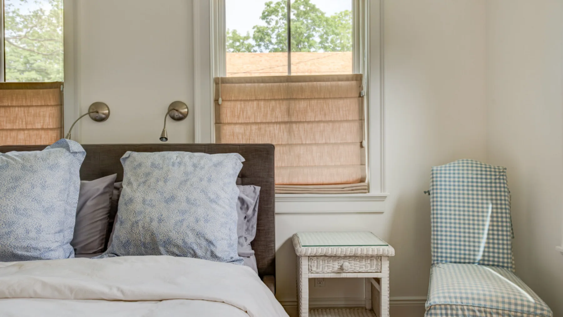 A bedroom with a bed beside a window with a lowered shade.