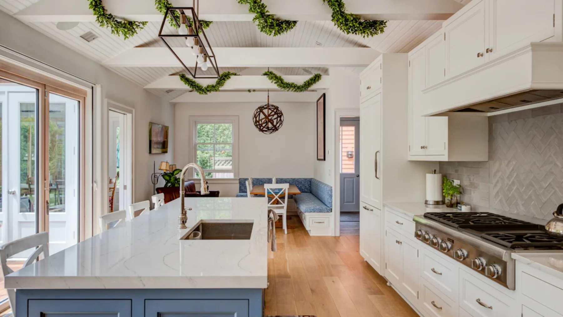 A bright kitchen with a large island, white cabinetry, and an adjoining seating area.