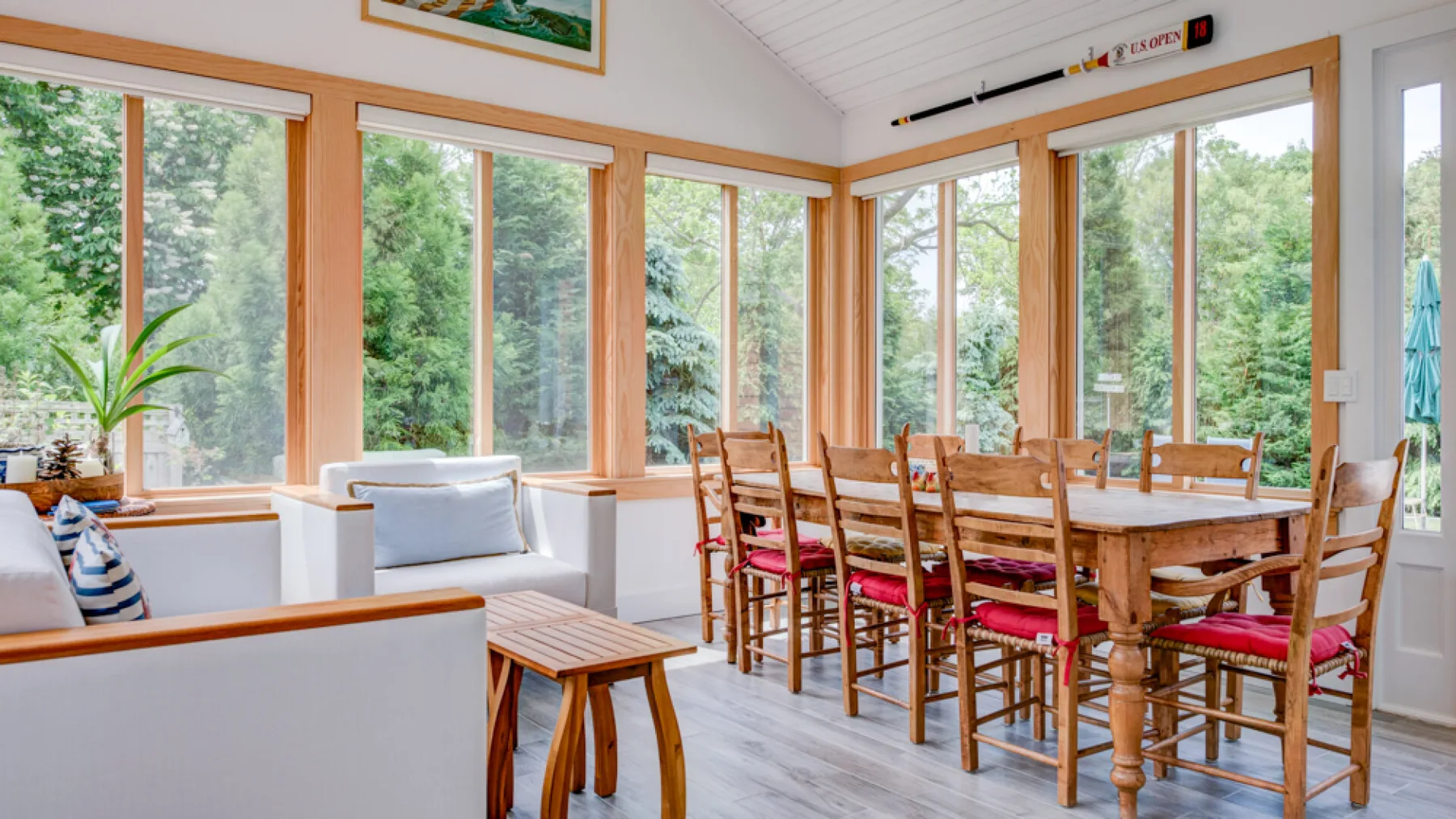 A bright dining area with a wooden table and large windows overlooking trees.