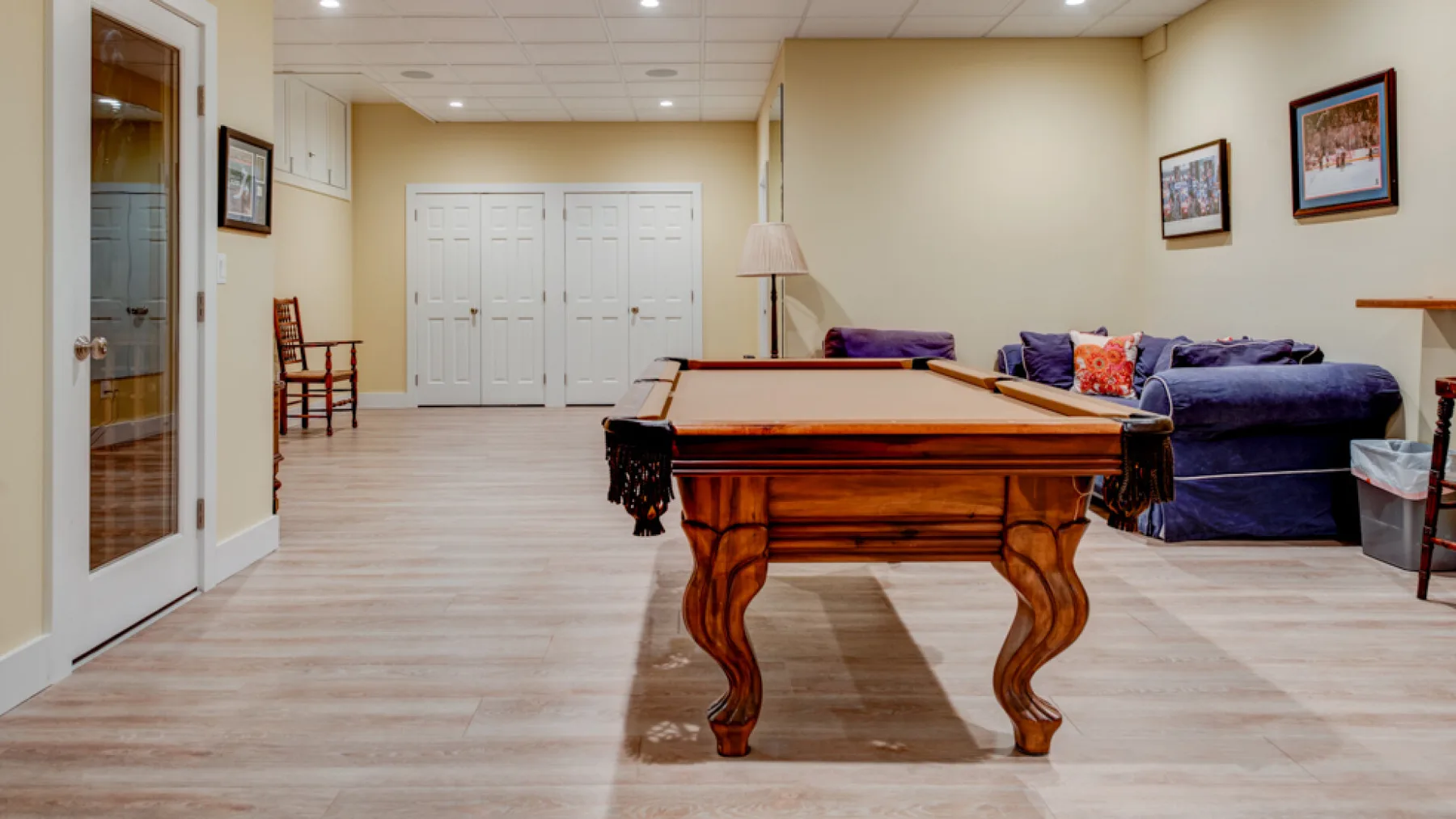 A game room with a pool table and seating along the wall.