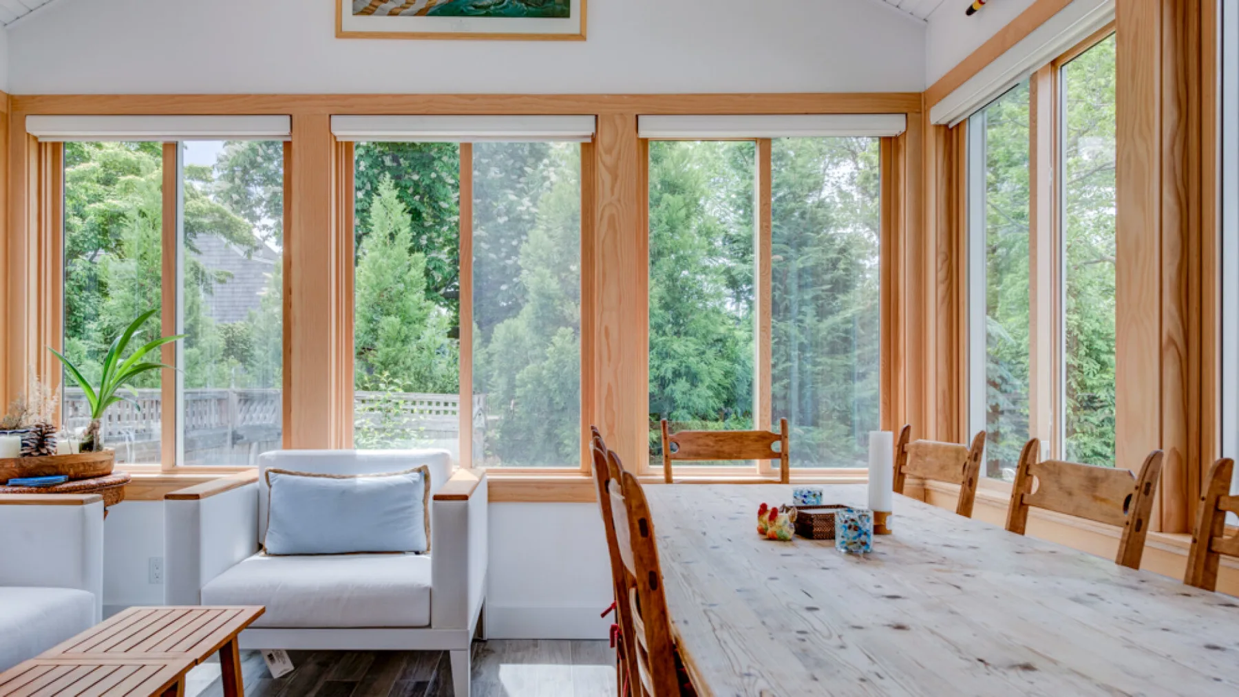 A bright dining area with a long wooden table beside large windows.