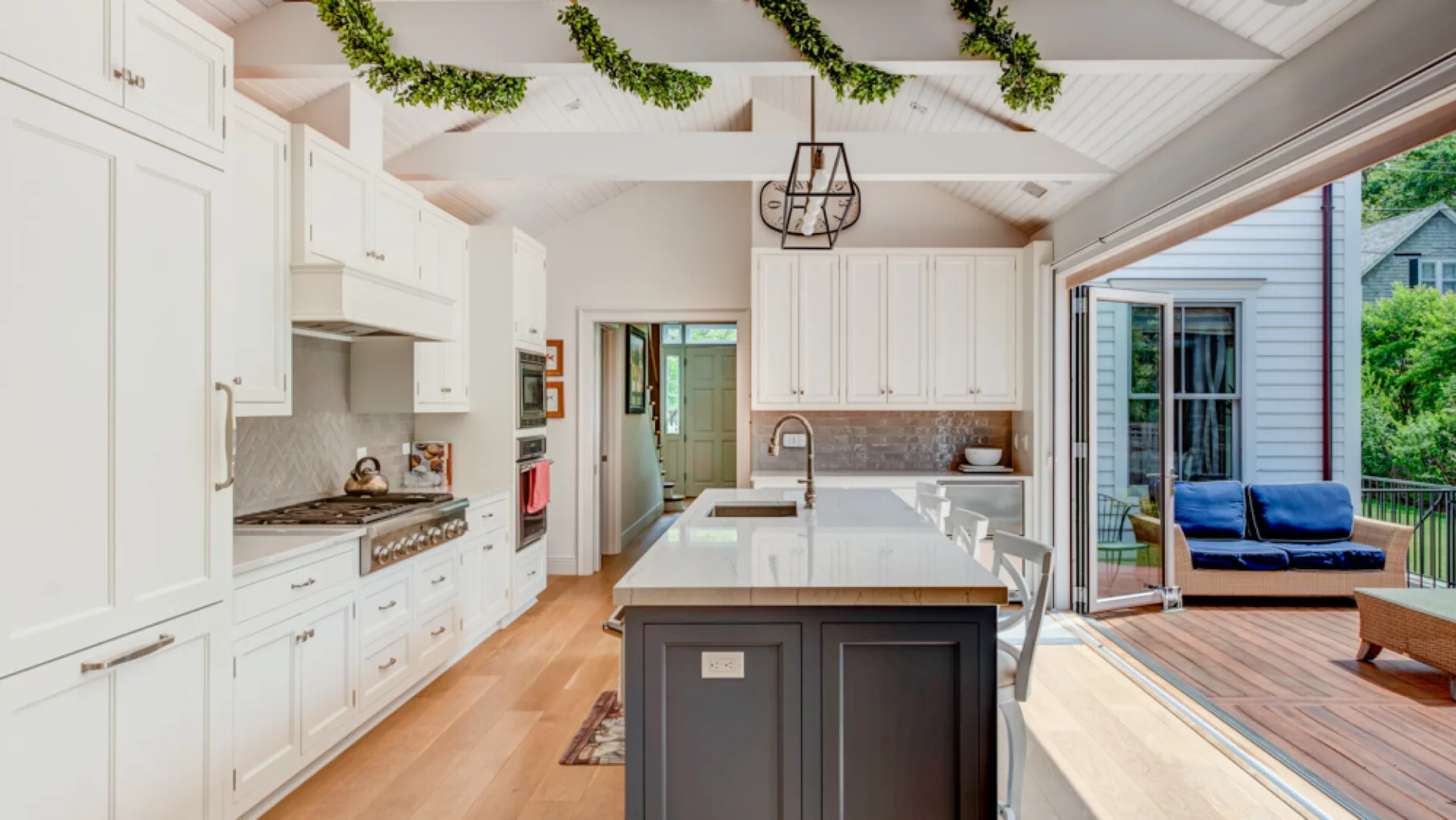 A bright kitchen with a large island and open doors to a deck.