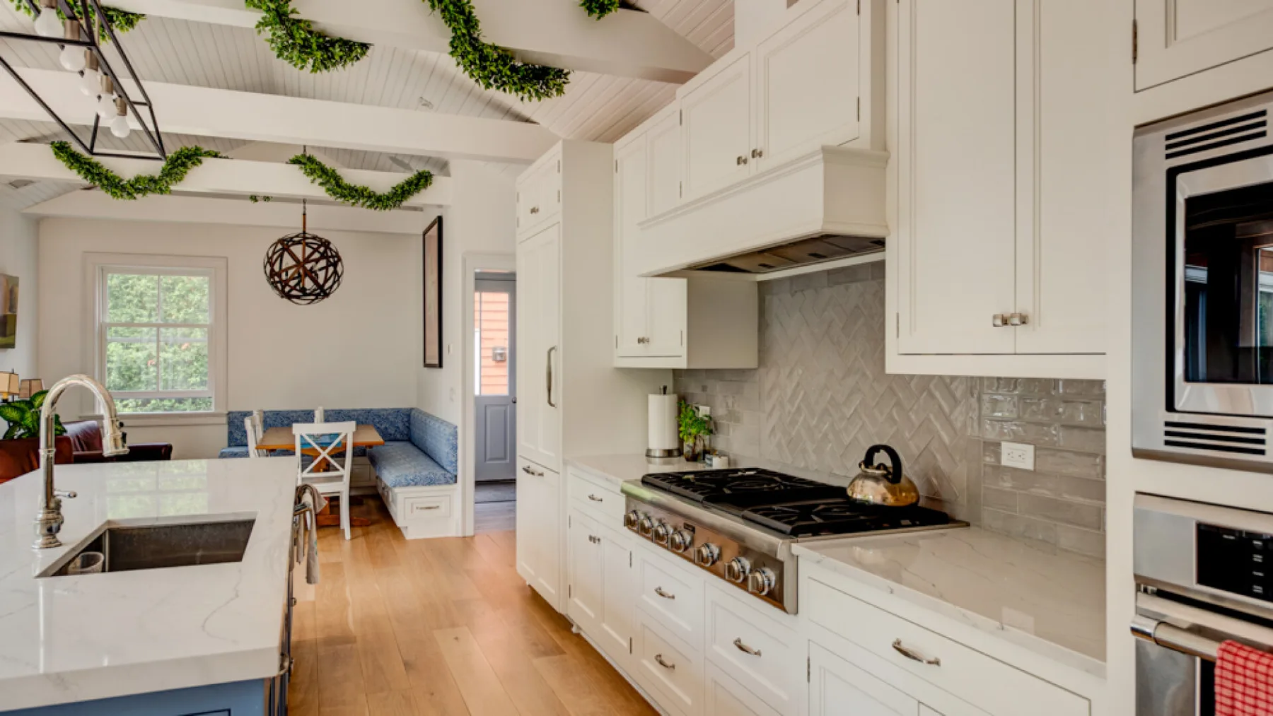 A bright kitchen with white cabinetry, a central island, and a dining area beyond.