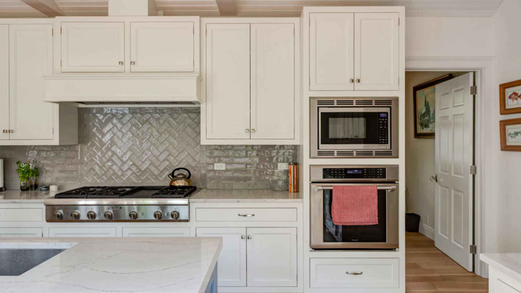 A bright kitchen with white cabinetry, a cooktop, and an island.