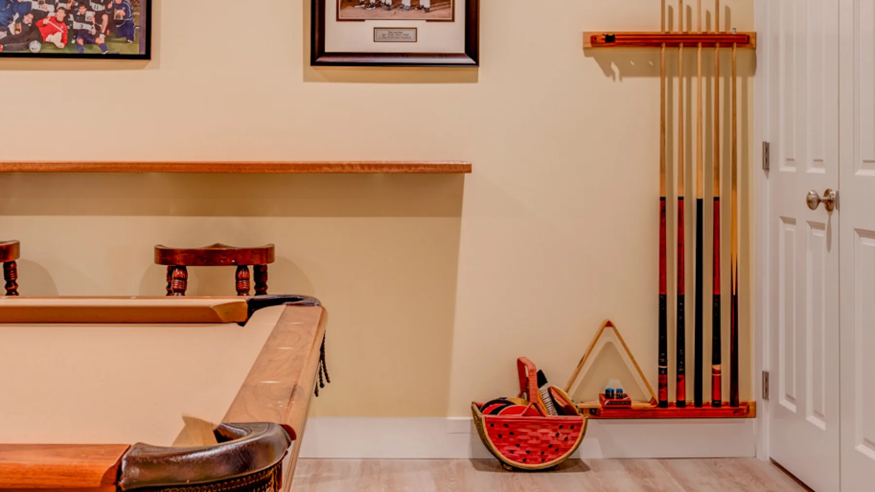 A billiards room with a pool table and cues stored on the wall.