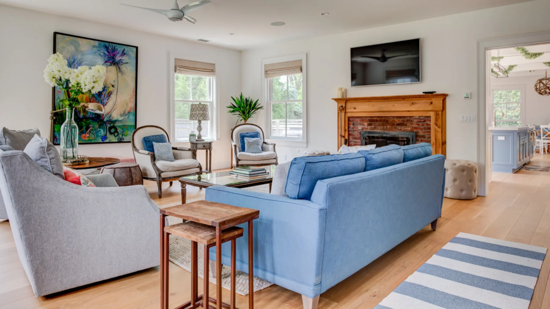 A bright living room with blue seating, a fireplace, and a television.