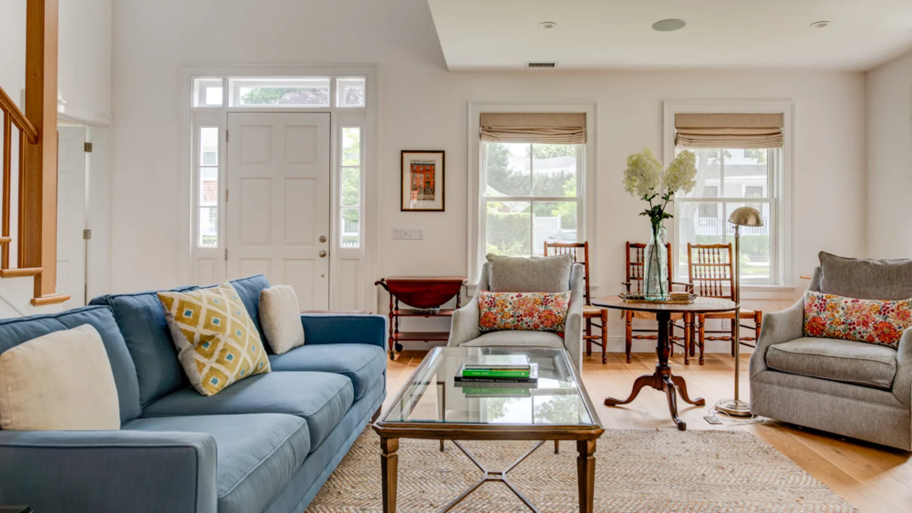A bright living room with blue seating and a glass coffee table.