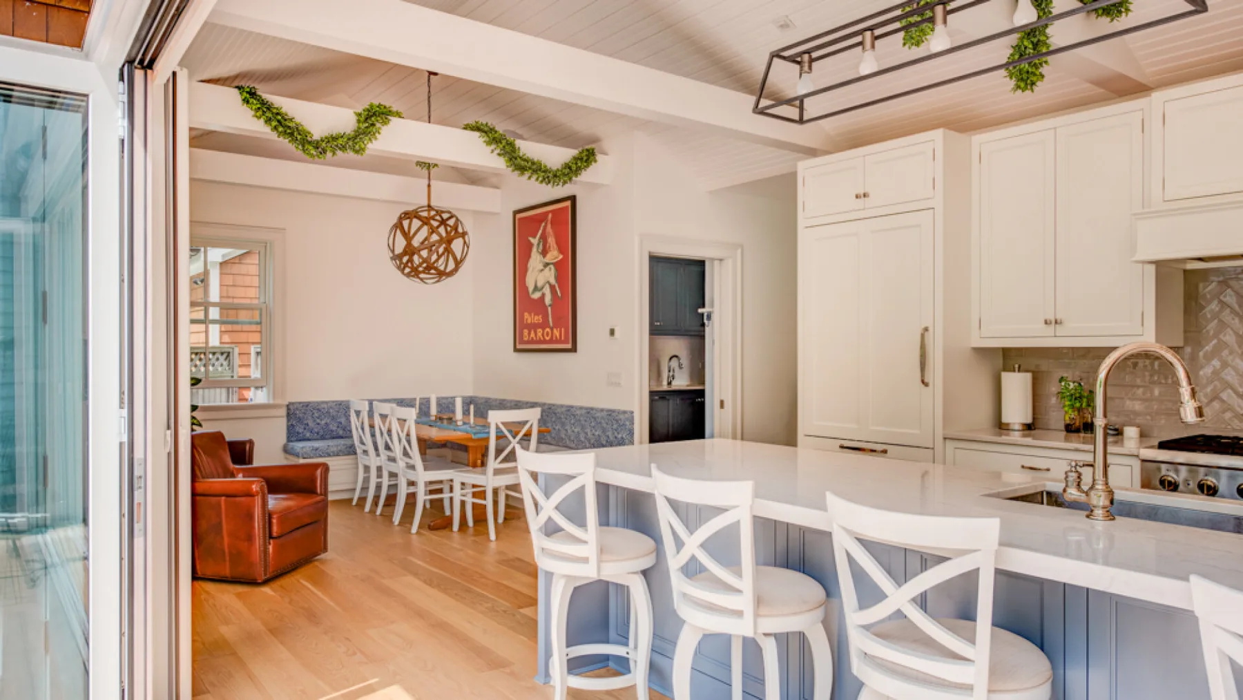 A bright kitchen and dining area with a long white island and dining table.