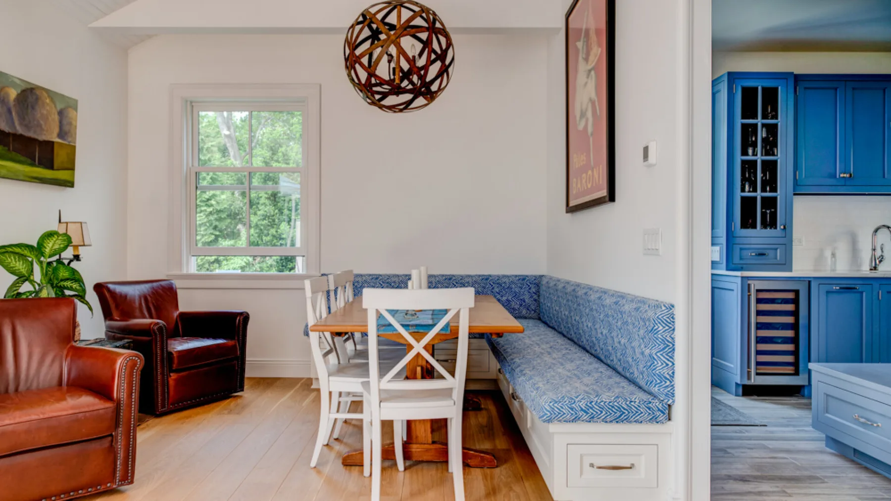 A bright dining nook with a table and chairs beside a blue built-in bench.