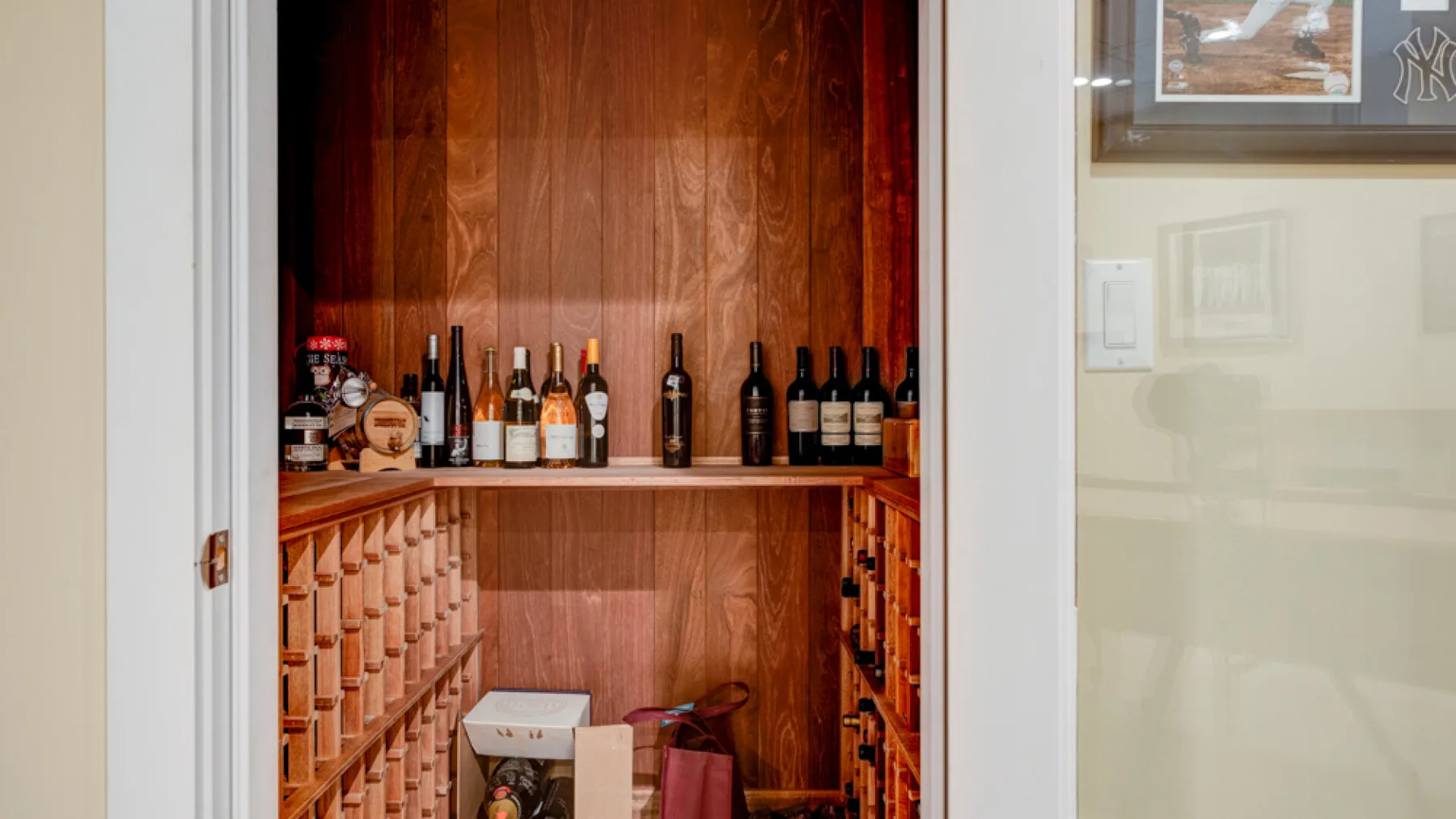A wine storage nook with bottles displayed on shelves and a small basin.