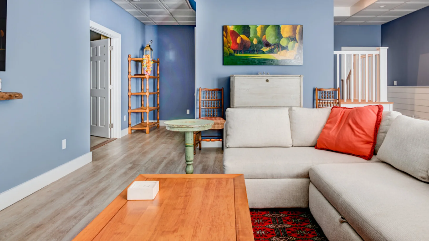 A living room with a sectional sofa, coffee table, and colorful wall art.