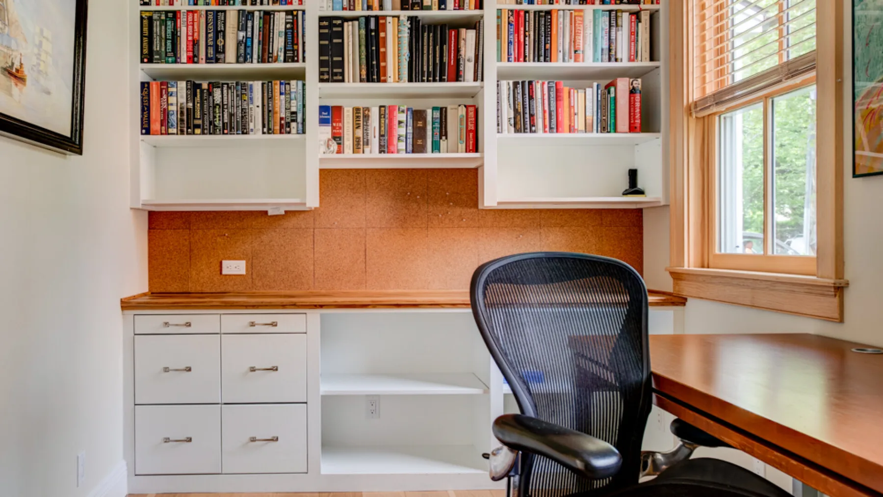 A study nook with built-in bookshelves, a desk, and a chair beside the window.
