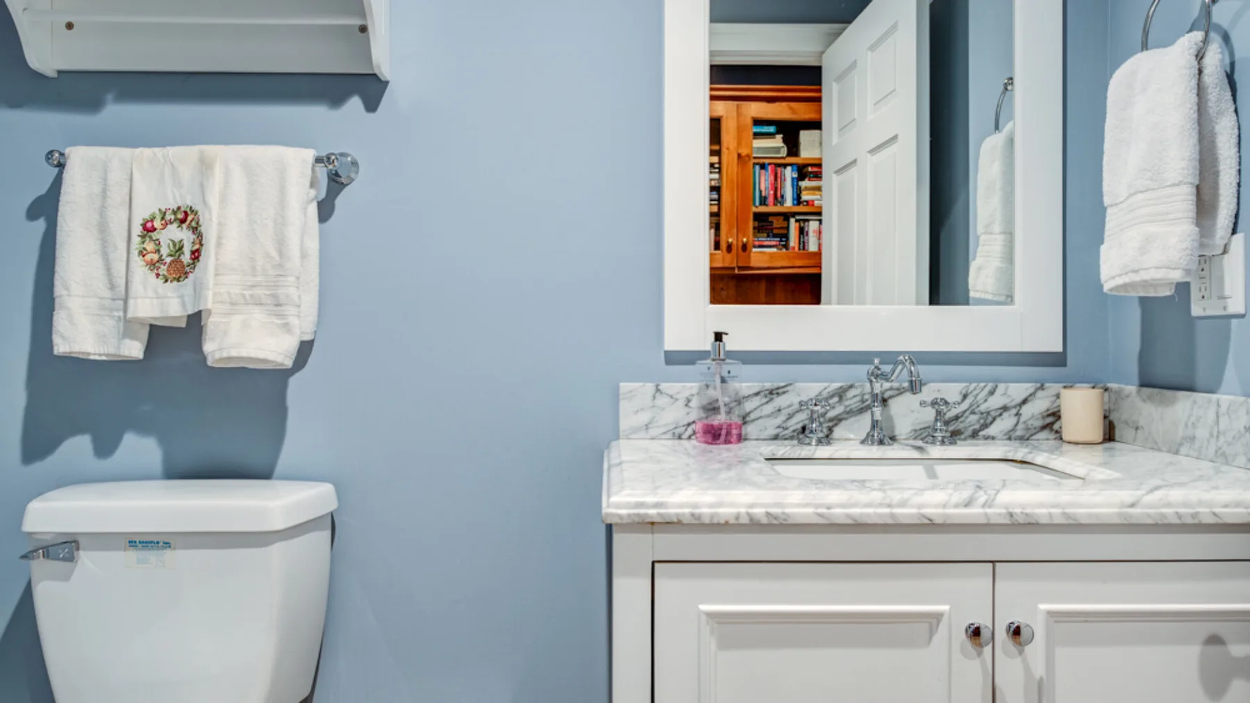 A bathroom vanity with a sink and mirror sits beside a toilet.