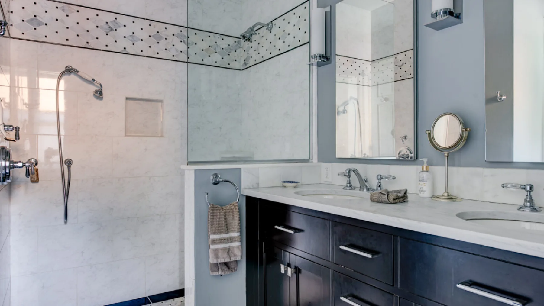 A tiled bathroom with a glass shower and a long vanity.