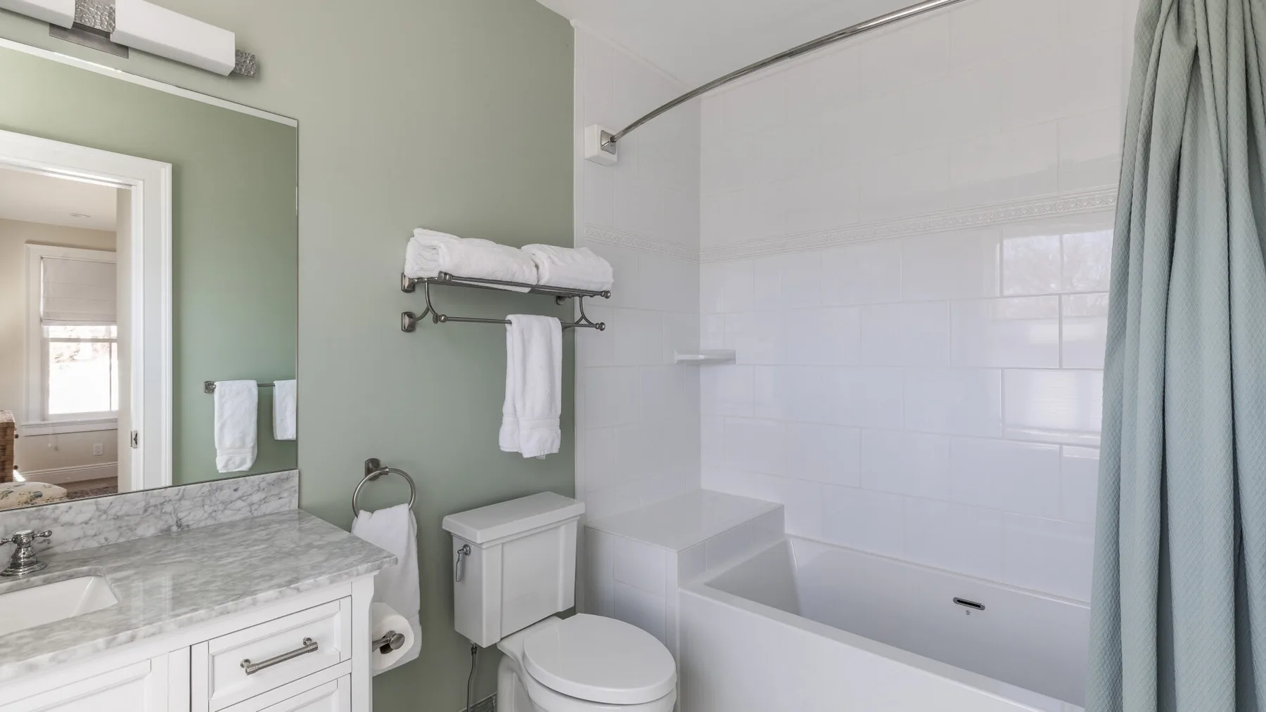 A bathroom with a sink, toilet, and bathtub behind a shower curtain.