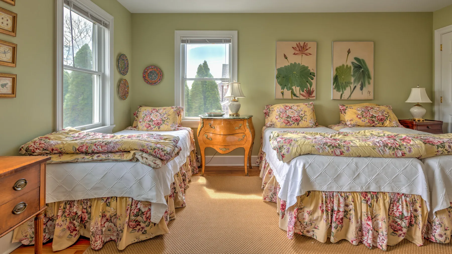 Un dormitorio con dos camas cubiertas de flores y una mesita entre ellas.