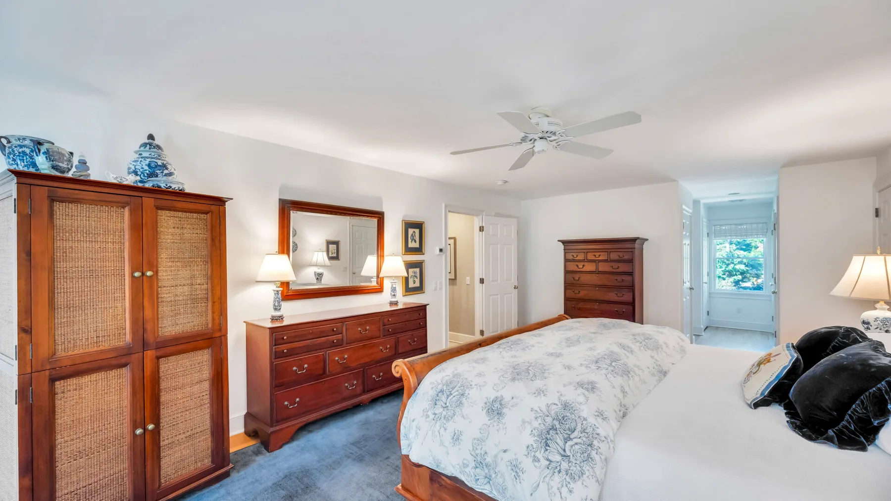 Un dormitorio con una cama grande, cómodas de madera y un ventilador de techo.