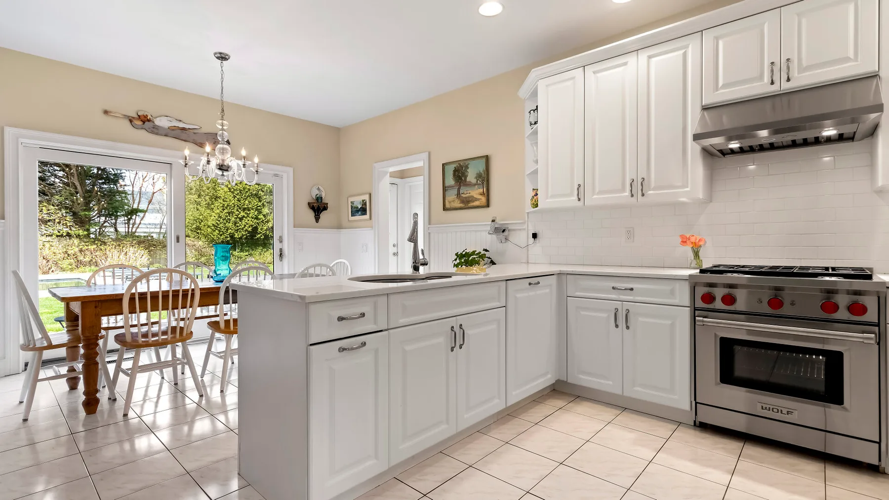 Una cocina luminosa con gabinetes blancos, una isla central y un comedor.