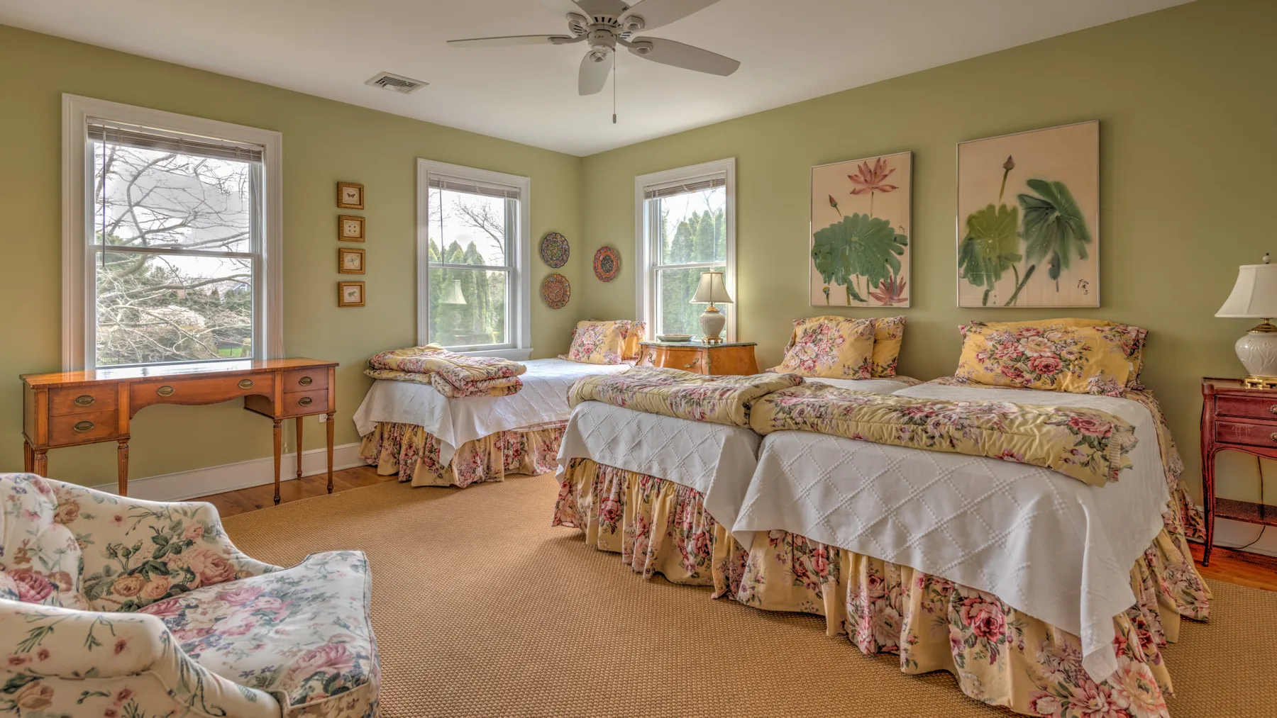 Un dormitorio con dos camas cubiertas con estampados florales y un sillón floral.