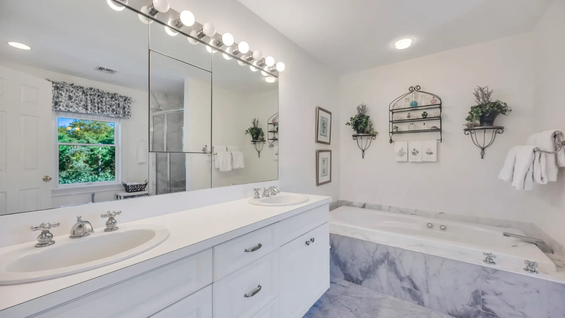 Un baño luminoso con un tocador largo, un espejo grande y una bañera.