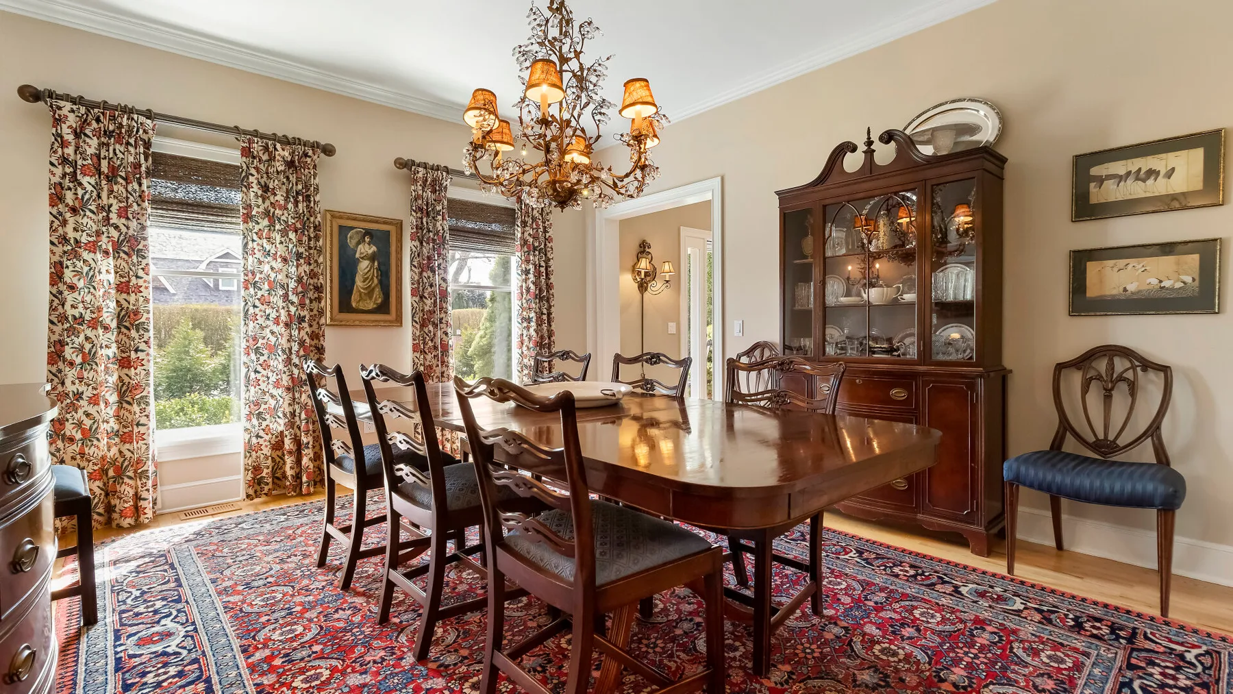 Un comedor formal con una mesa larga de madera, sillas y una alfombra estampada.