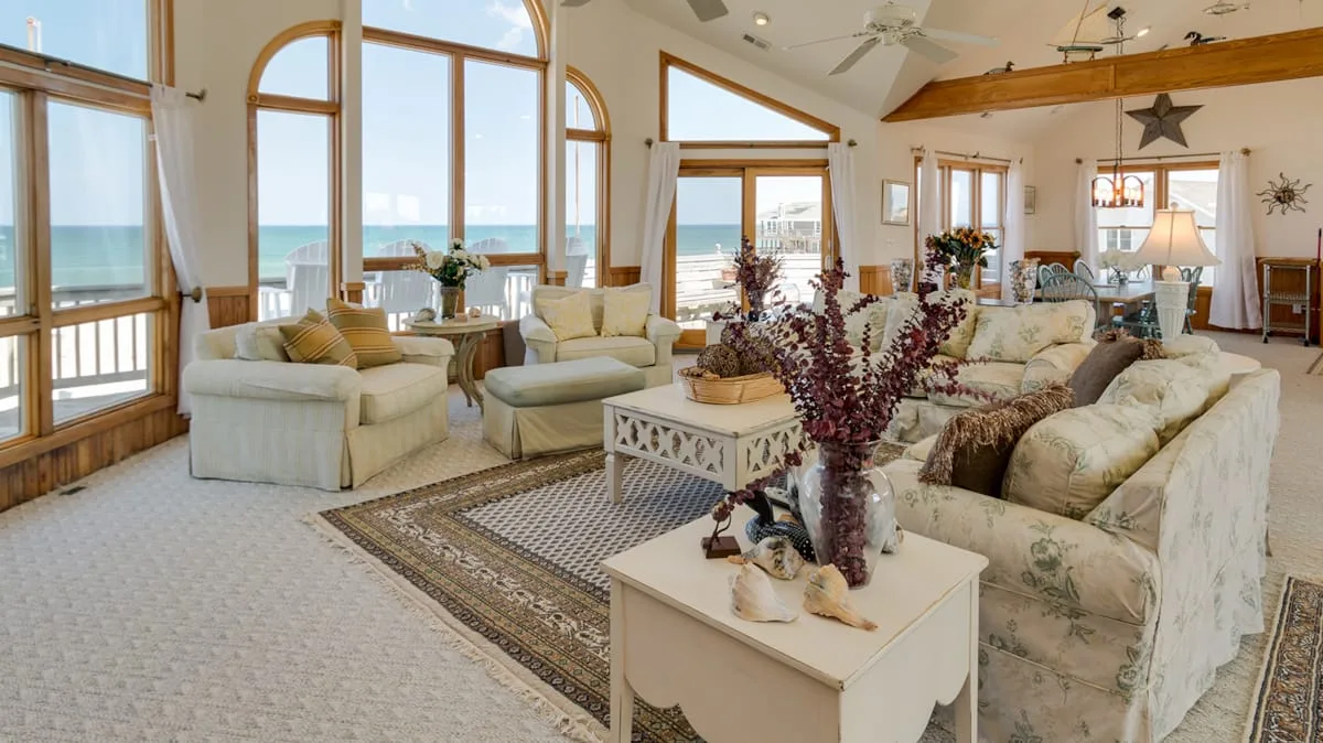 A bright living room with seating, large windows, and an ocean view.