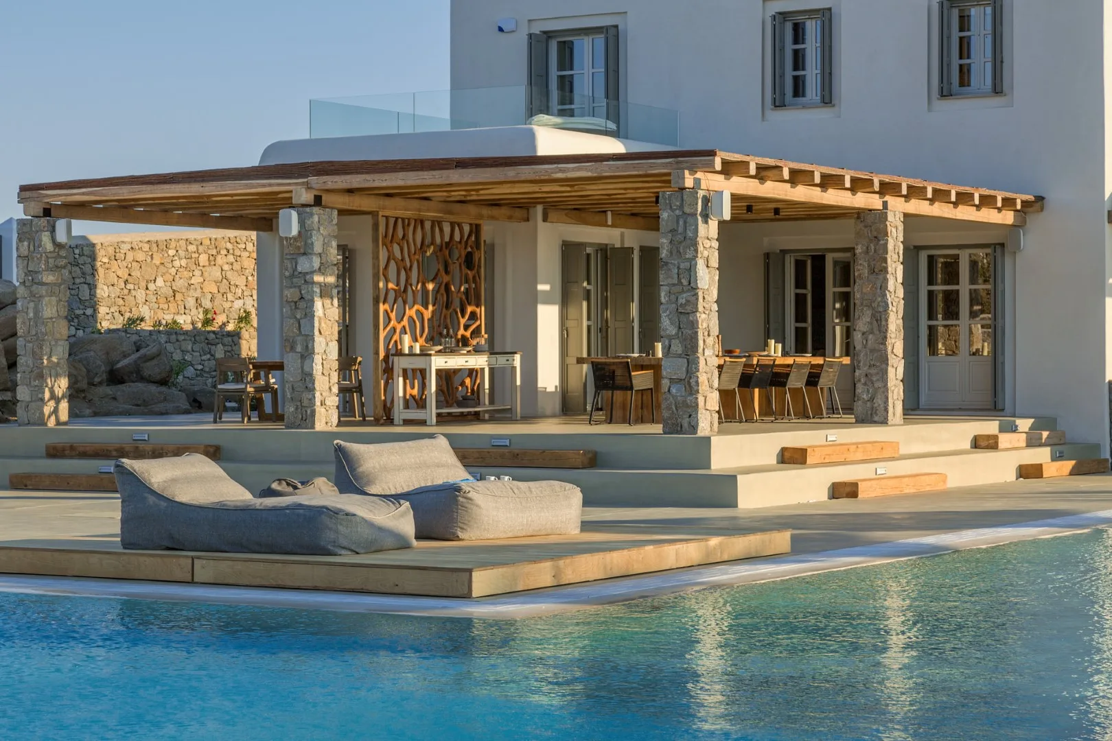 A poolside patio with outdoor seating beside a modern house.