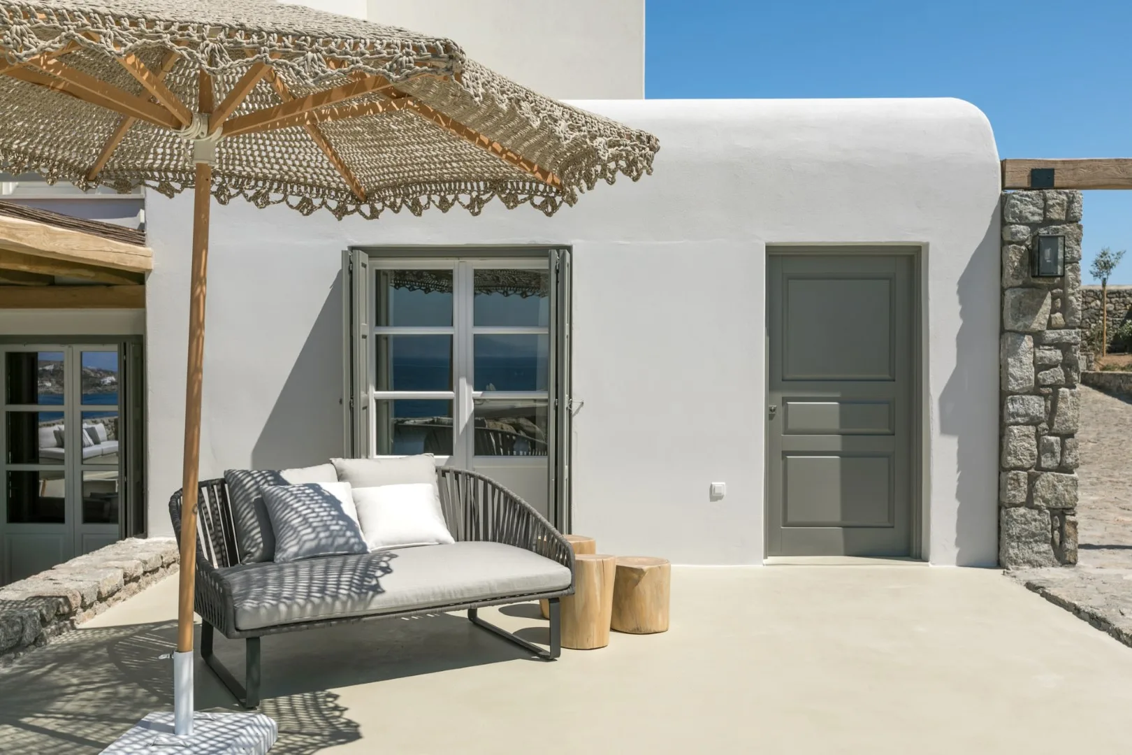 A shaded outdoor seating area sits beside a white building.