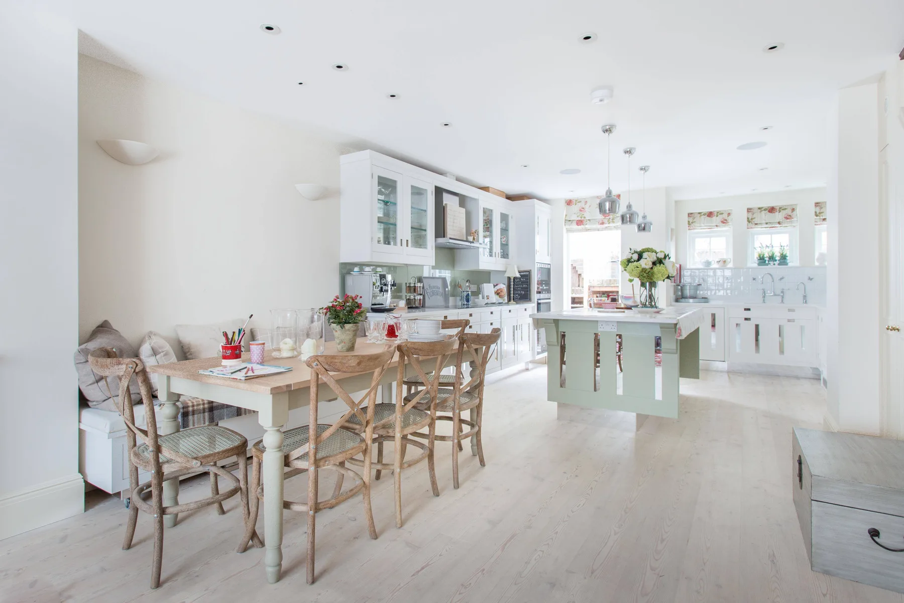 Una cocina y comedor luminosos con una isla central y asientos de madera.
