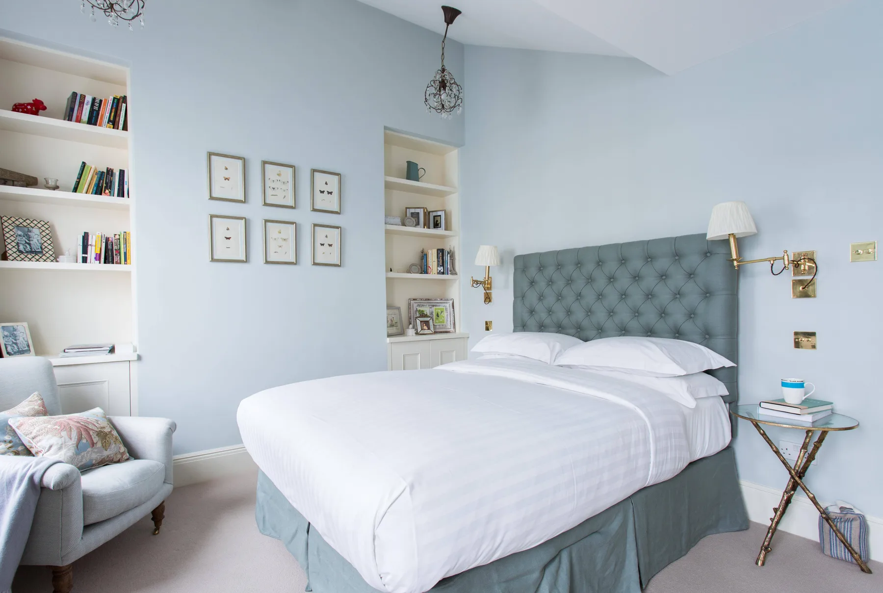 Un dormitorio con una cama grande, un cabecero acolchado y estanterías empotradas.