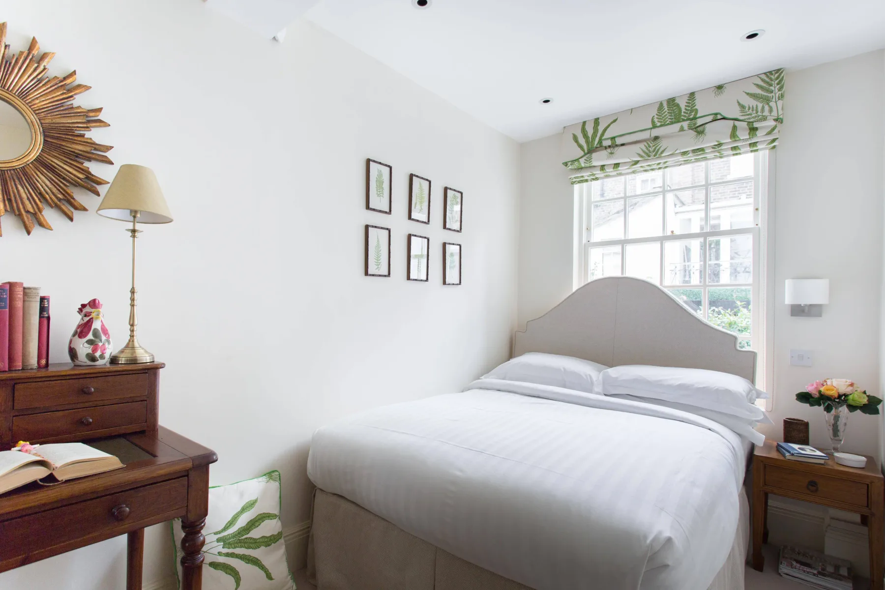 Un dormitorio luminoso con una cama bien tendida junto a una gran ventana.