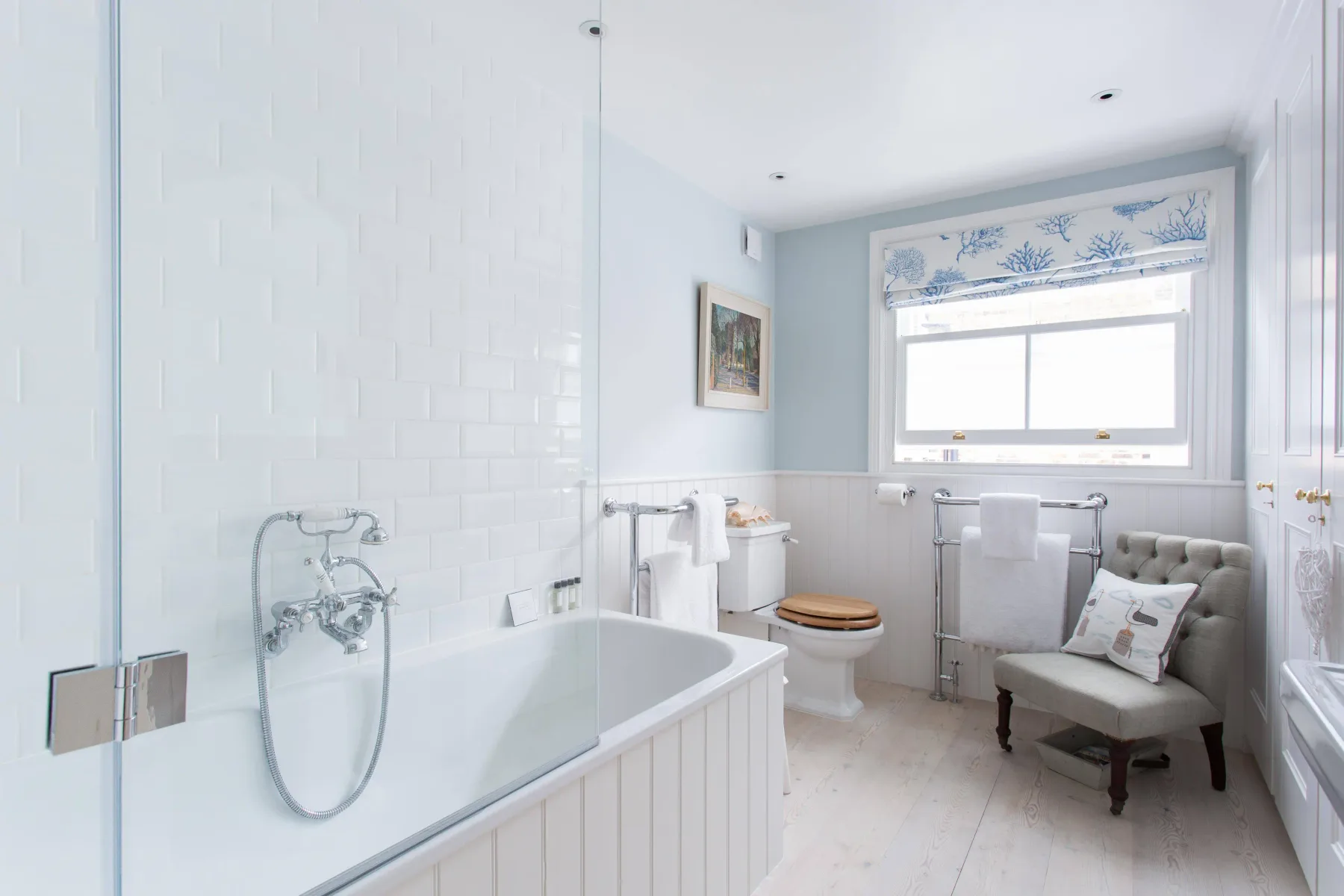 Un baño luminoso con bañera, inodoro y asientos junto a una ventana.