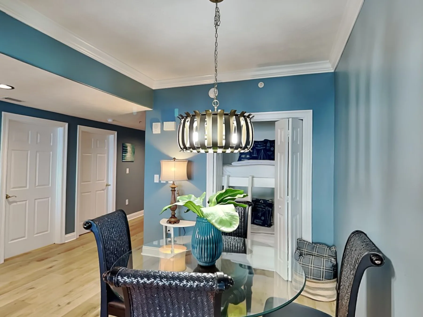 A dining area with a glass table and a hanging light.