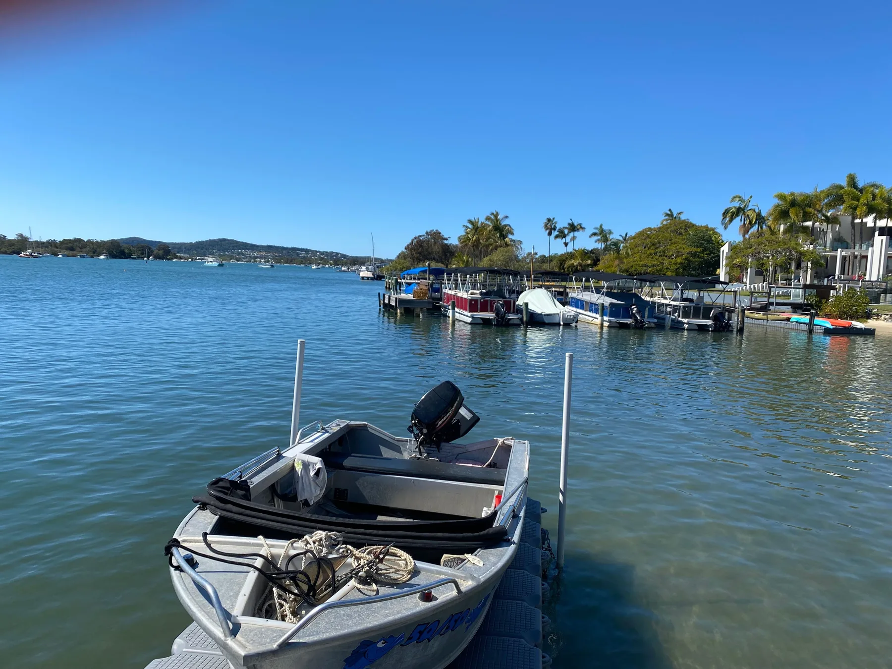 Una pequeña embarcación está amarrada en aguas tranquilas junto a una marina.