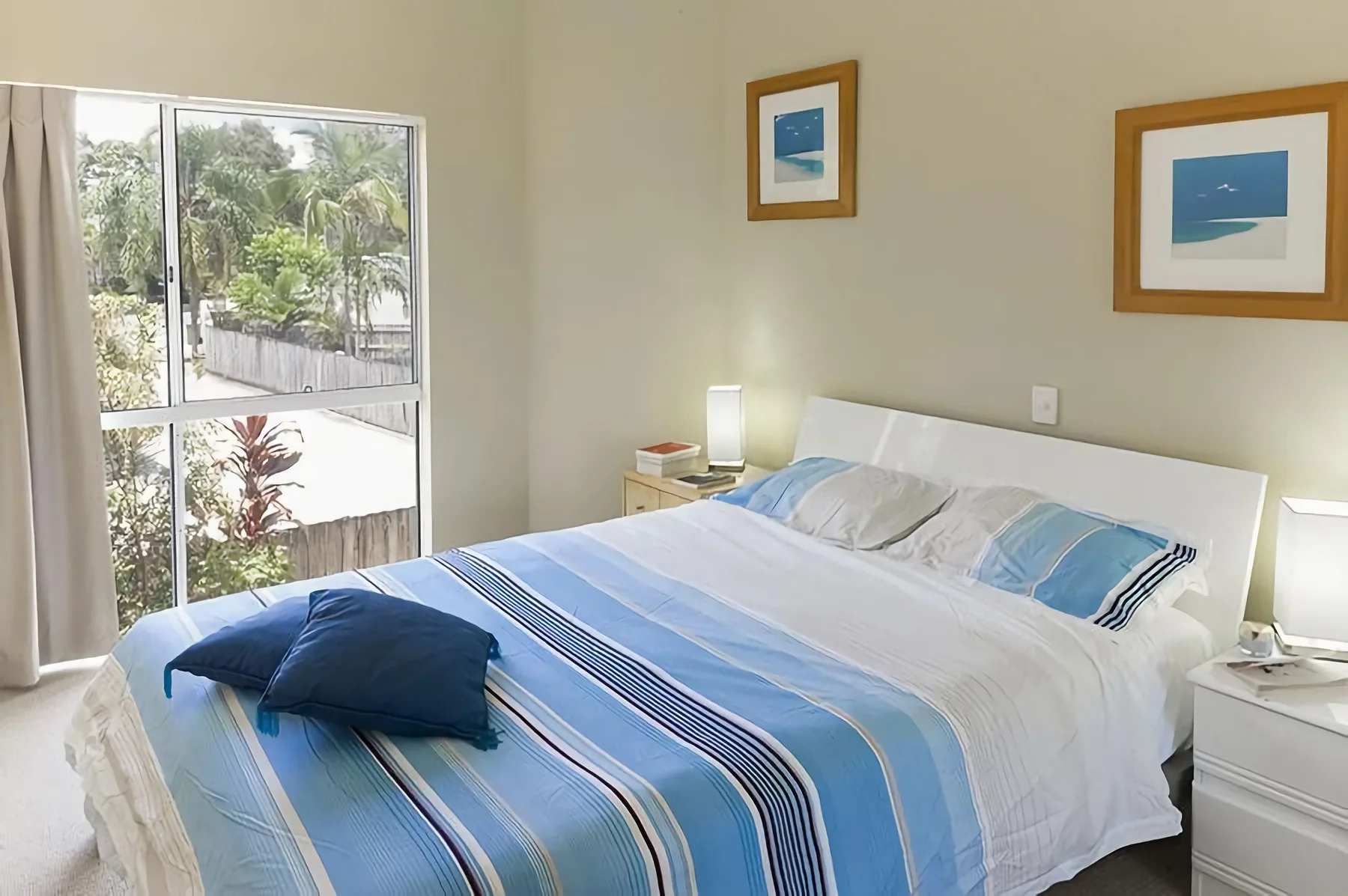 Un dormitorio con una cama bien arreglada y ropa de cama azul y blanca.