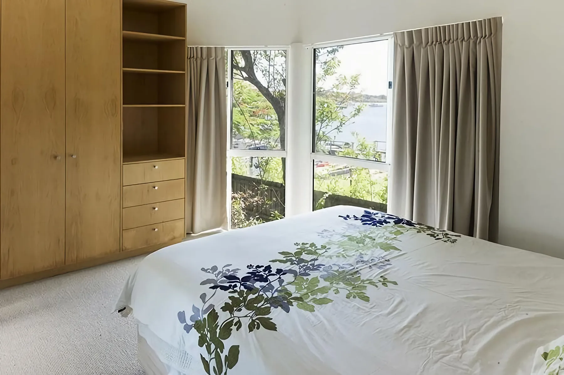 Un dormitorio con una cama junto a grandes ventanas y cortinas.