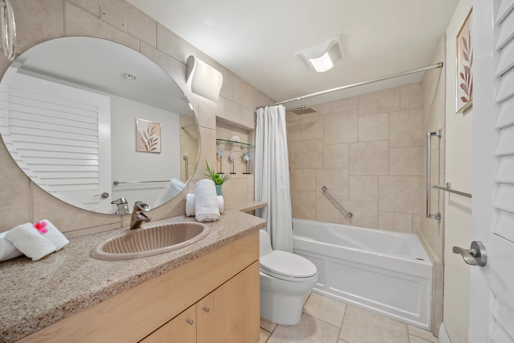 Baño con paredes de azulejos, lavabo, inodoro y bañera detrás de una cortina.