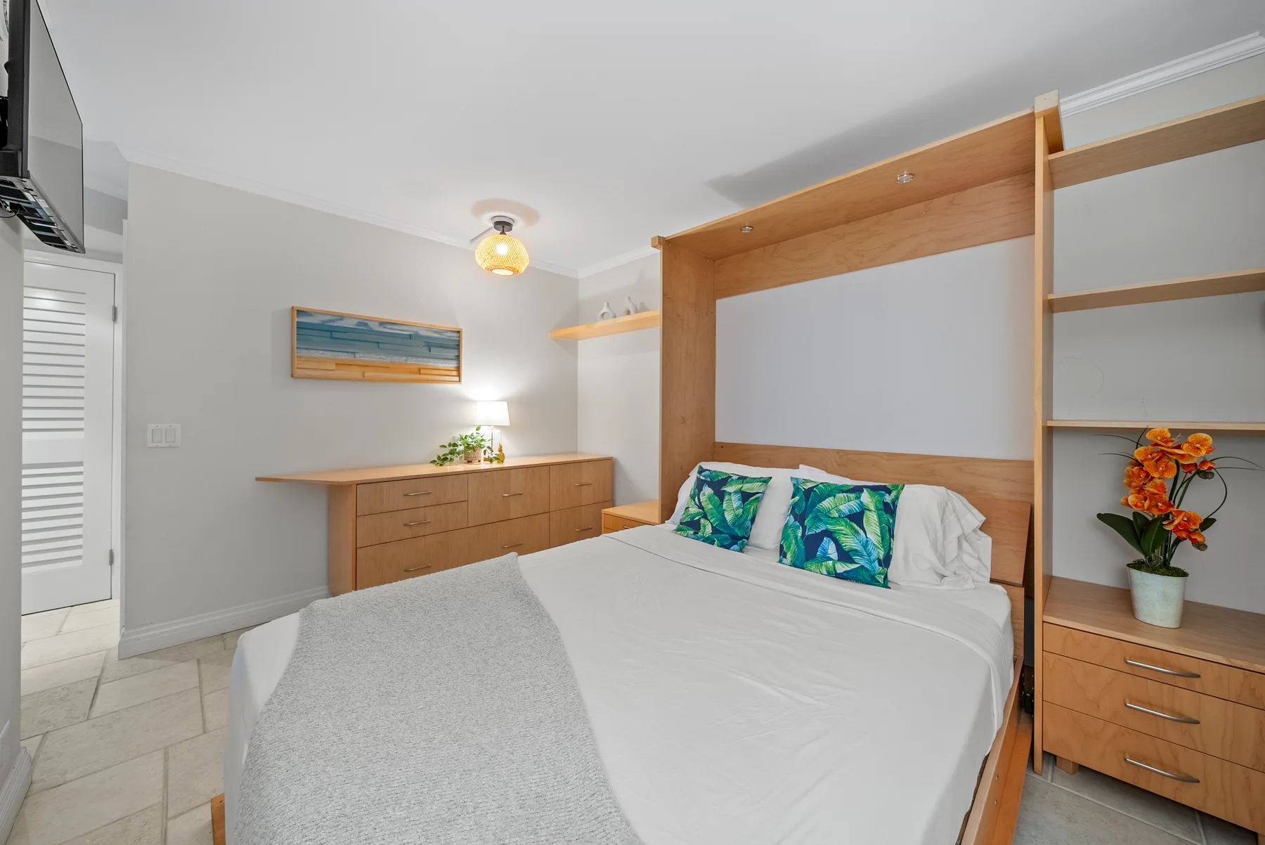 Un dormitorio con una cama bien tendida y estanterías de madera integradas.
