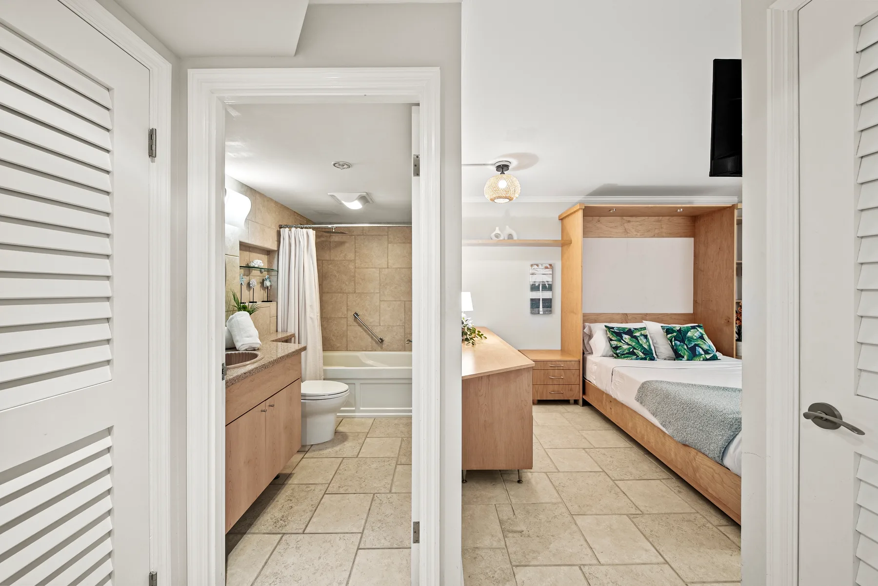 Un dormitorio con una cama y estanterías empotradas junto a un baño abierto.