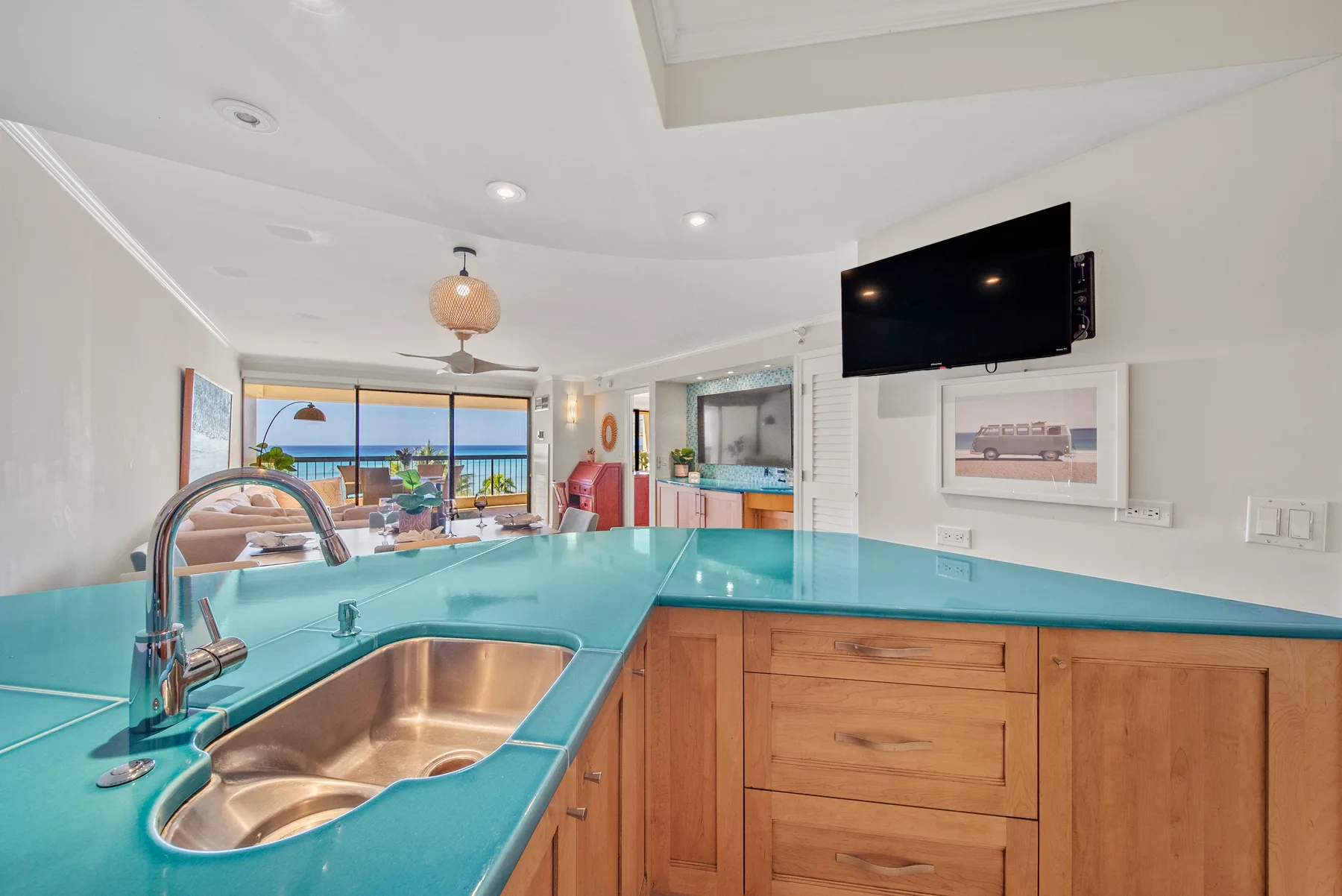 Una cocina con una encimera turquesa, gabinetes de madera y un televisor sobre la encimera.