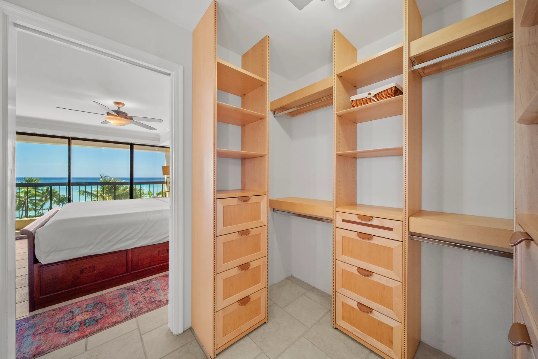 Un vestidor con estantes y cajones de madera da a un dormitorio.