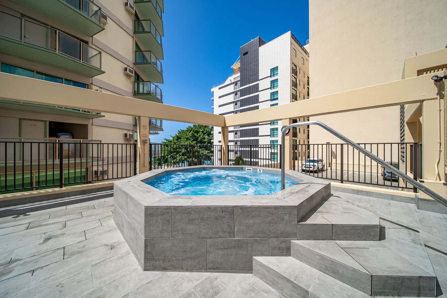 Una piscina en la azotea ocupa una terraza pavimentada entre edificios de apartamentos.