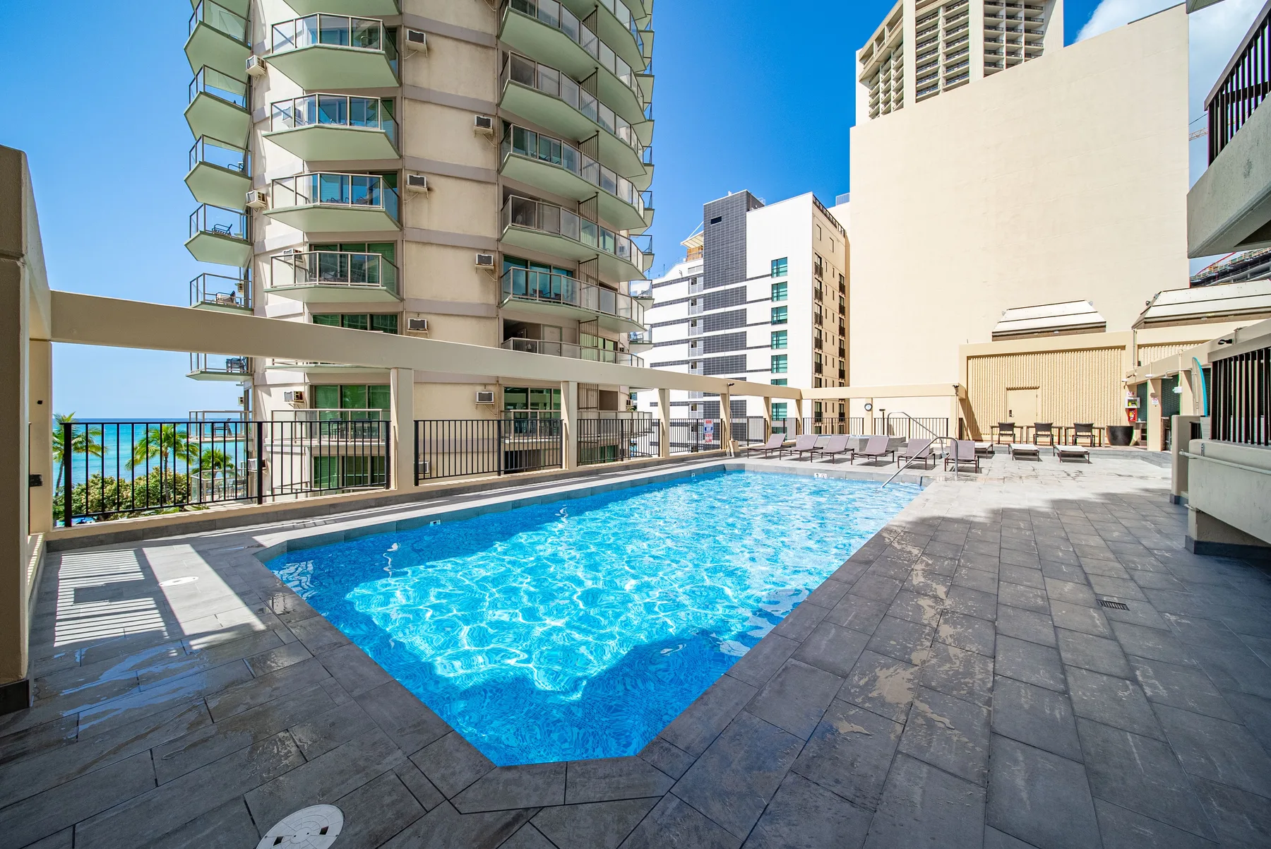 Una piscina al aire libre está rodeada de edificios altos de apartamentos bajo un cielo despejado.