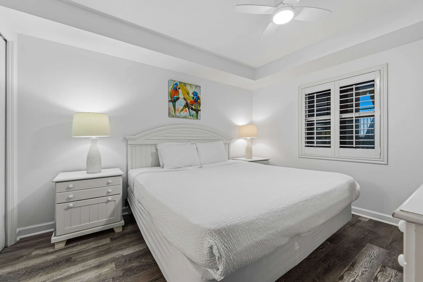 A bright bedroom with a neatly made bed and a window with blinds.