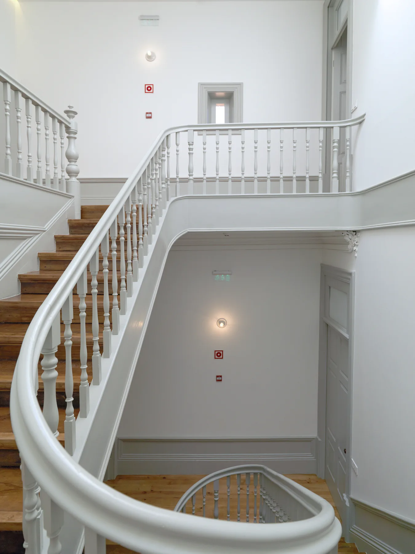 Una escalera interior luminosa con escalones de madera y barandillas blancas.