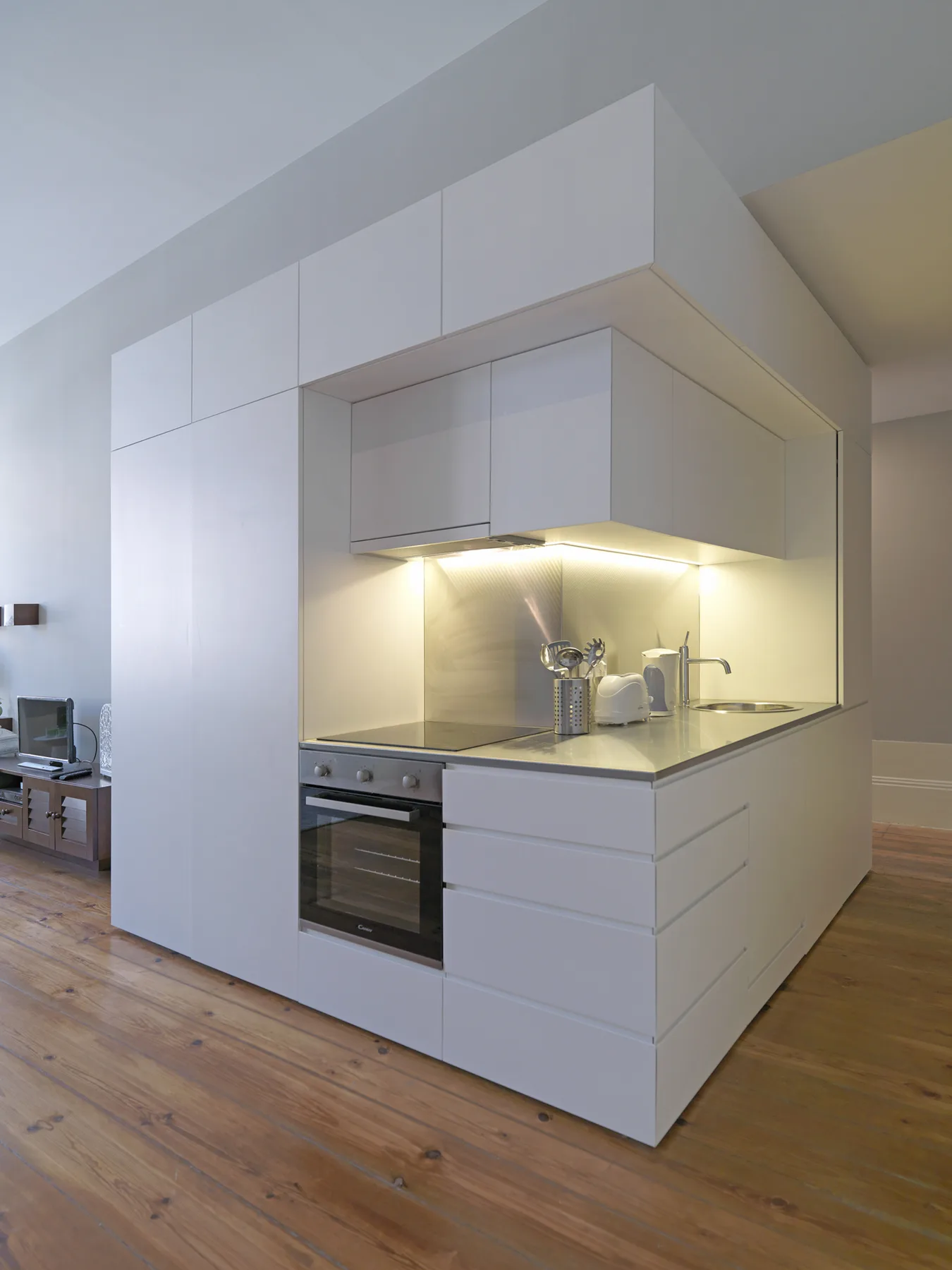 Una cocina moderna con armarios blancos, una encimera y un horno integrado.