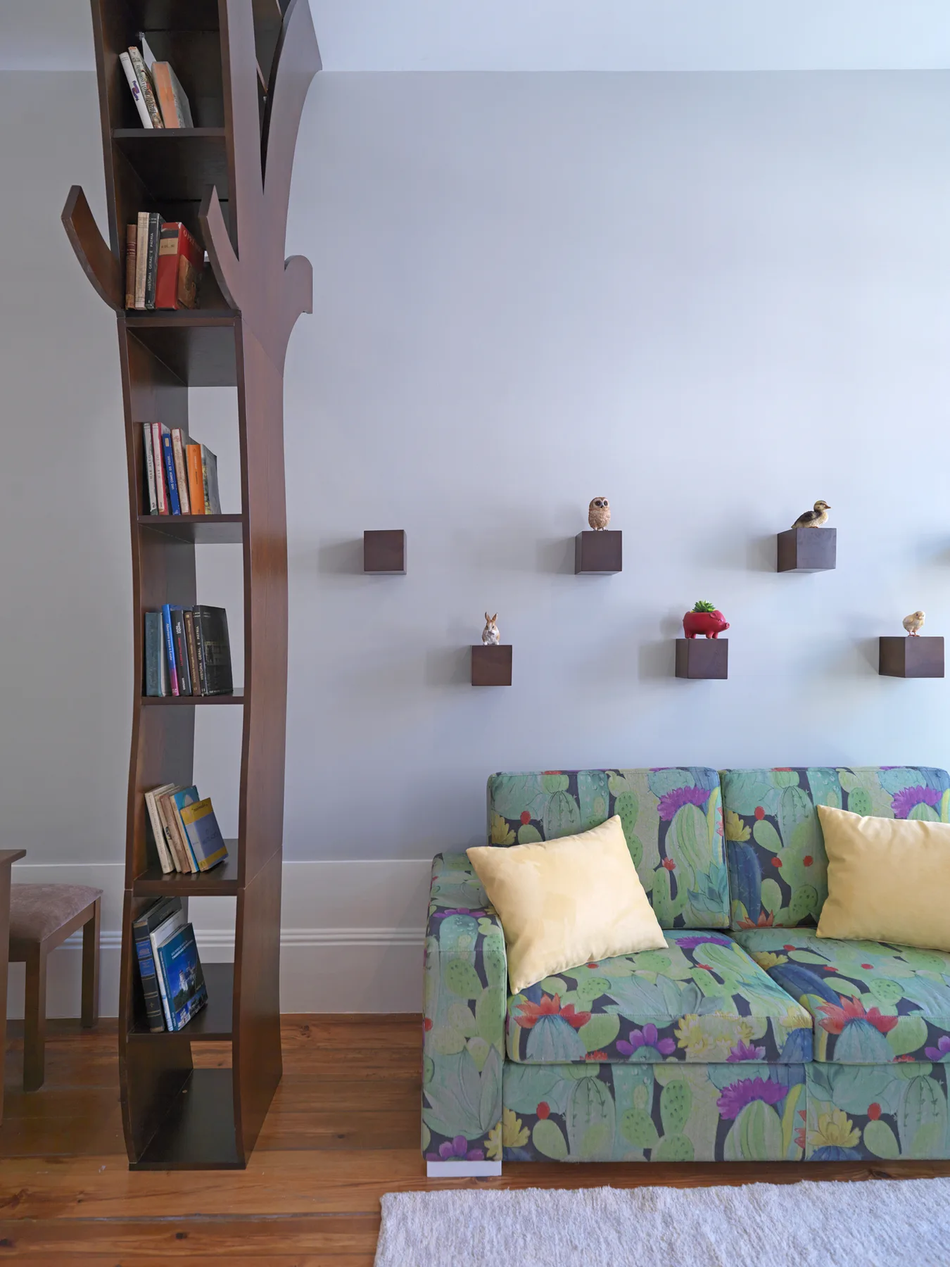 Una sala de estar con un sofá estampado colorido, cojines y estantes de pared.